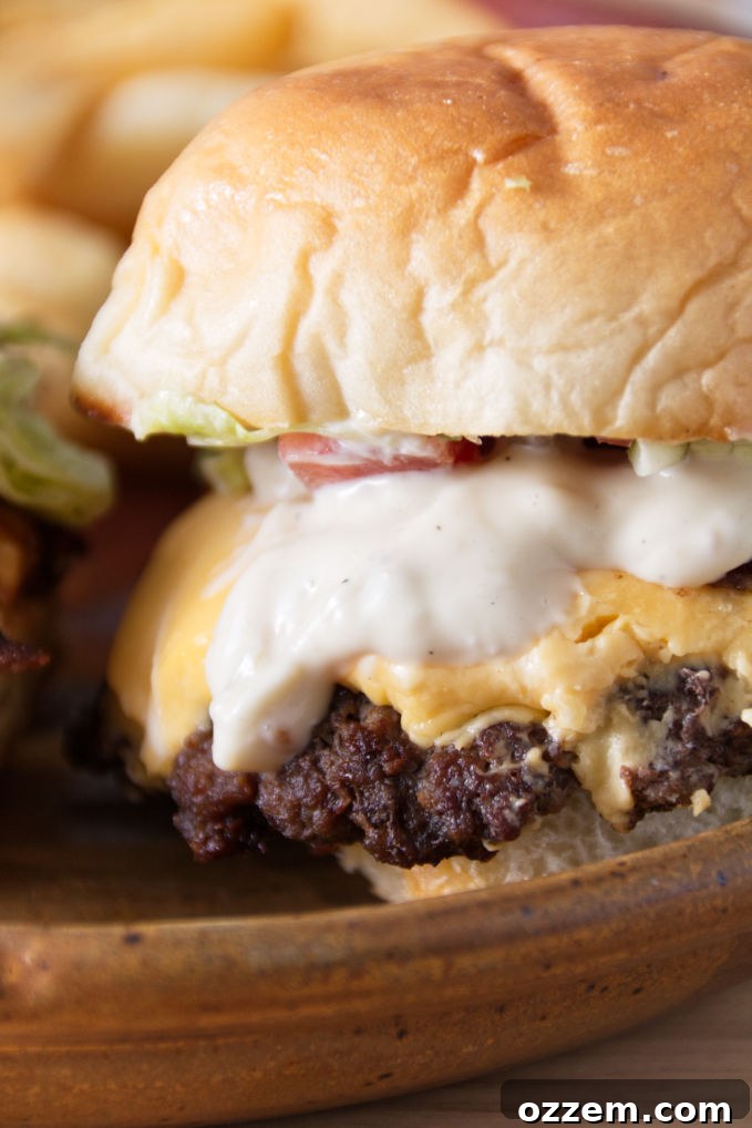 A delicious cheesy slider with vibrant green lettuce, a perfectly grilled patty, and creamy Donkey Sauce oozing out, resting on a rustic ceramic plate. A perfect bite for any burger enthusiast.