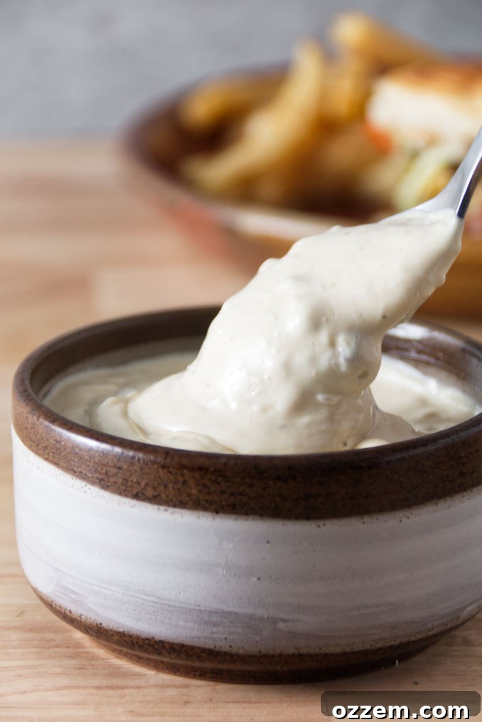 A ceramic bowl filled with creamy, rich Donkey Sauce, with a spoon dipping into its depths, showcasing its perfect consistency and inviting texture.