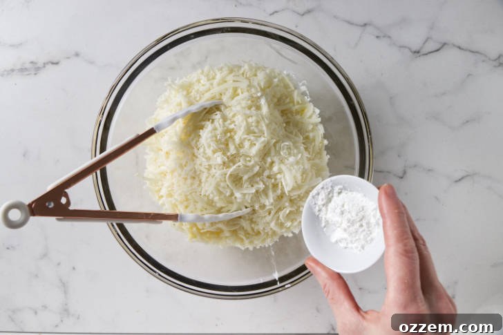 Shredded Jarlsberg and Pecorino Romano cheeses being combined with a small amount of cornstarch in a bowl.