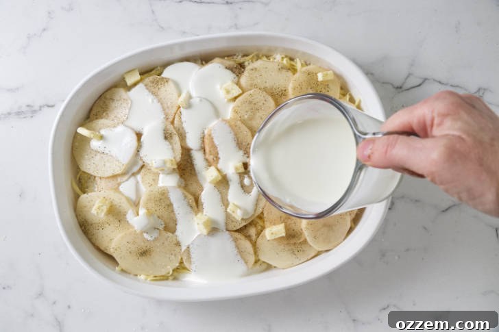 Pats of butter placed on a layer of potatoes, followed by a generous pour of seasoned cream.