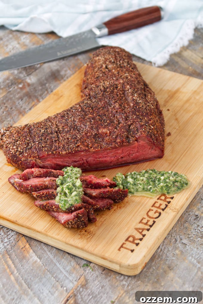 Traeger smoked tri-tip sliced on a cutting board topped with chimichurri