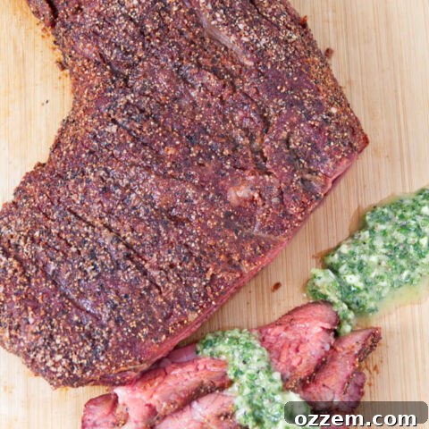Traeger smoked tri-tip sliced on a cutting board topped with chimichurri