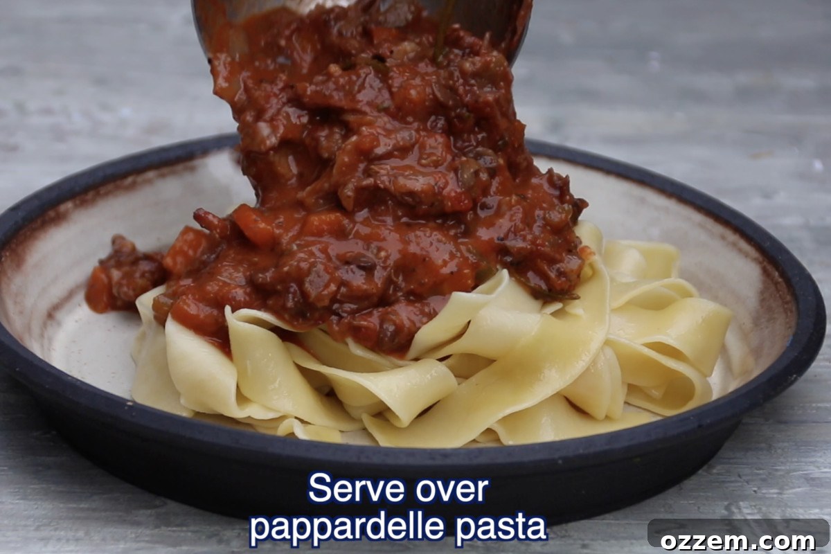 pouring ragu over pappardelle pasta on plate