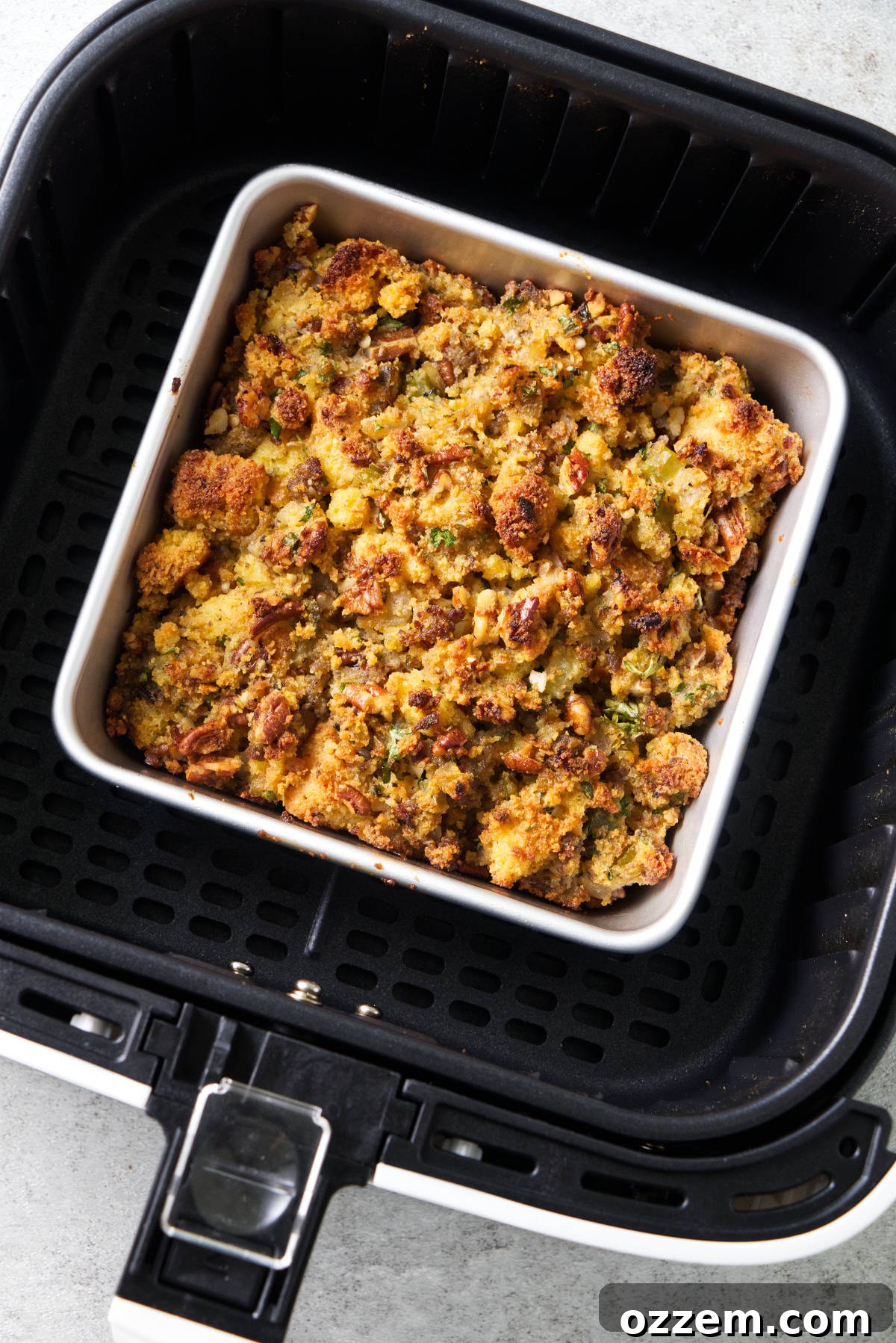 A baking dish filled with savory air fryer stuffing, golden-brown and crispy on top, resting inside an air fryer basket, ready to be served.