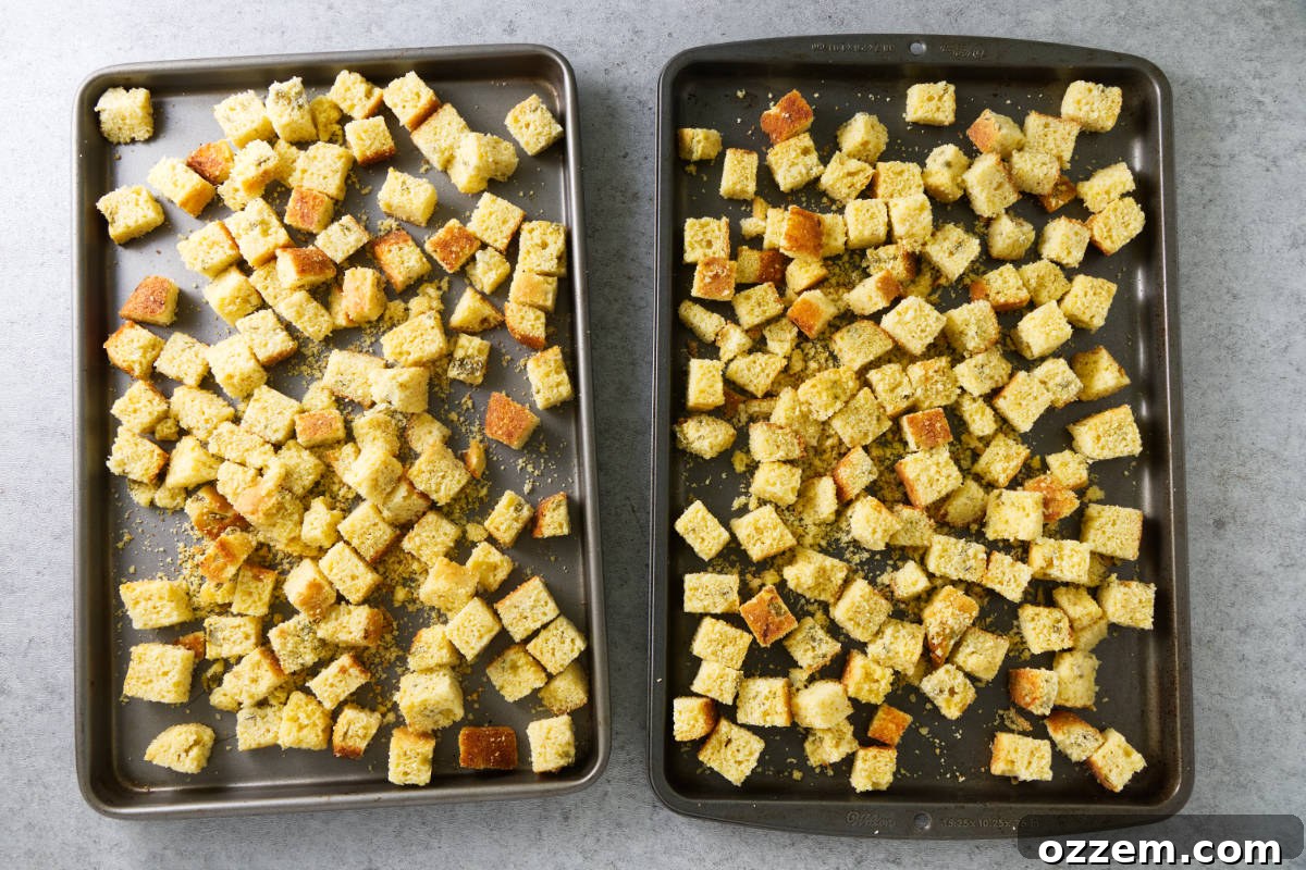 Cornbread cubes spread on baking trays, drying and toasting on a Traeger grill, essential for perfect smoked stuffing.