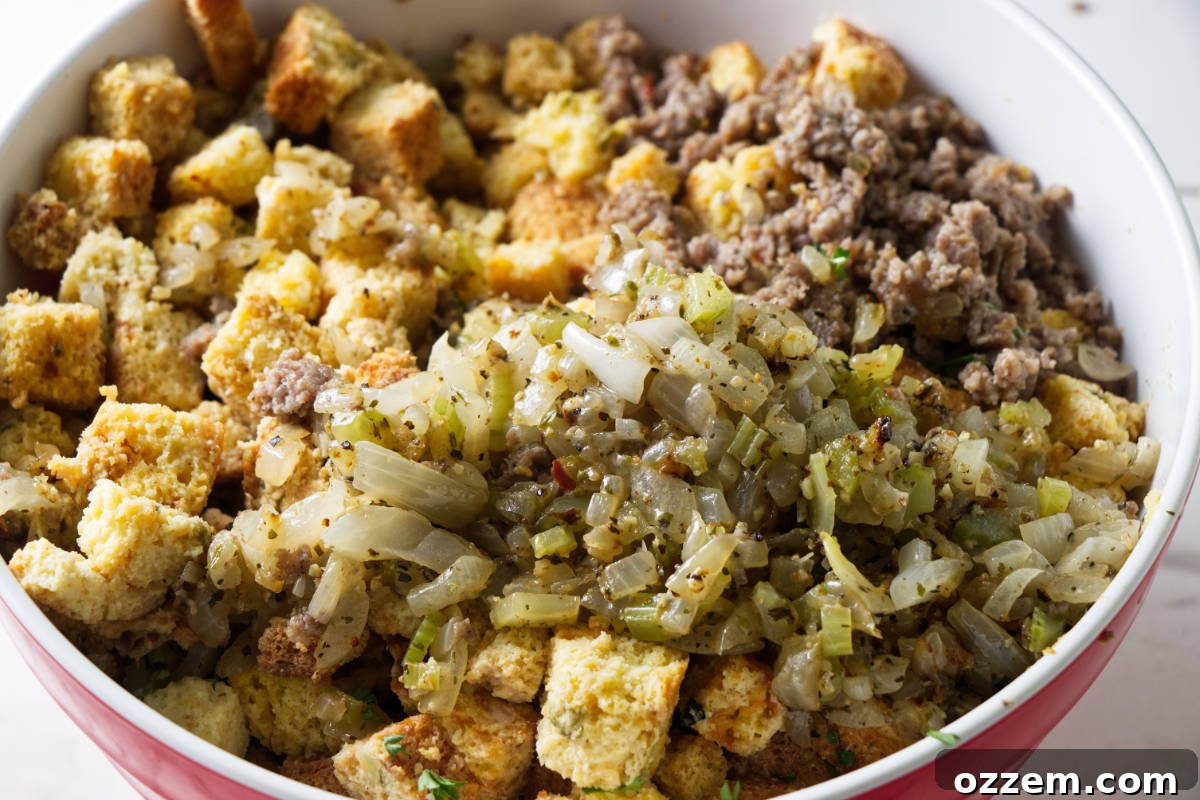 Combining toasted cornbread, browned sausage, and sautéed vegetables with liquid ingredients in a large bowl for smoking.