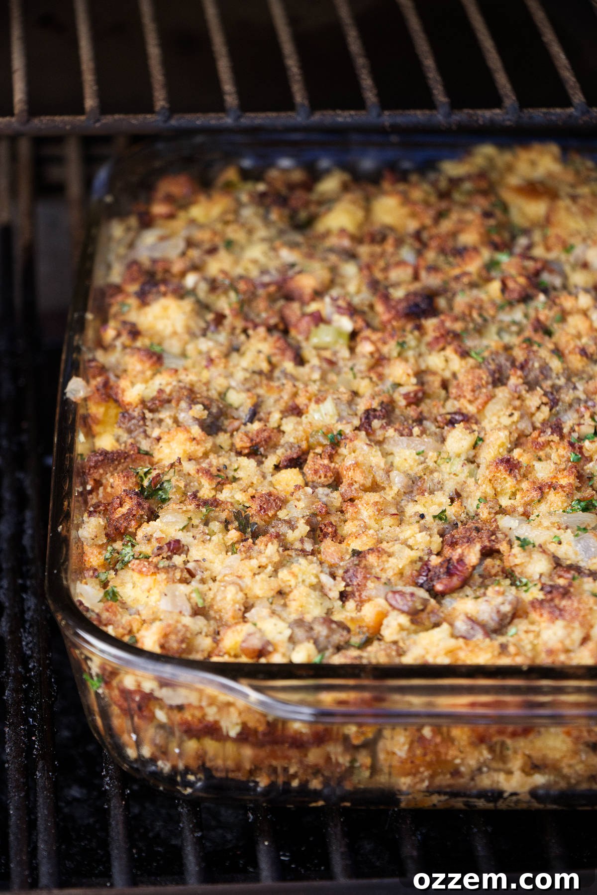 A casserole dish filled with Traeger smoked cornbread stuffing, baking inside a Traeger pellet grill, acquiring smoky flavor.