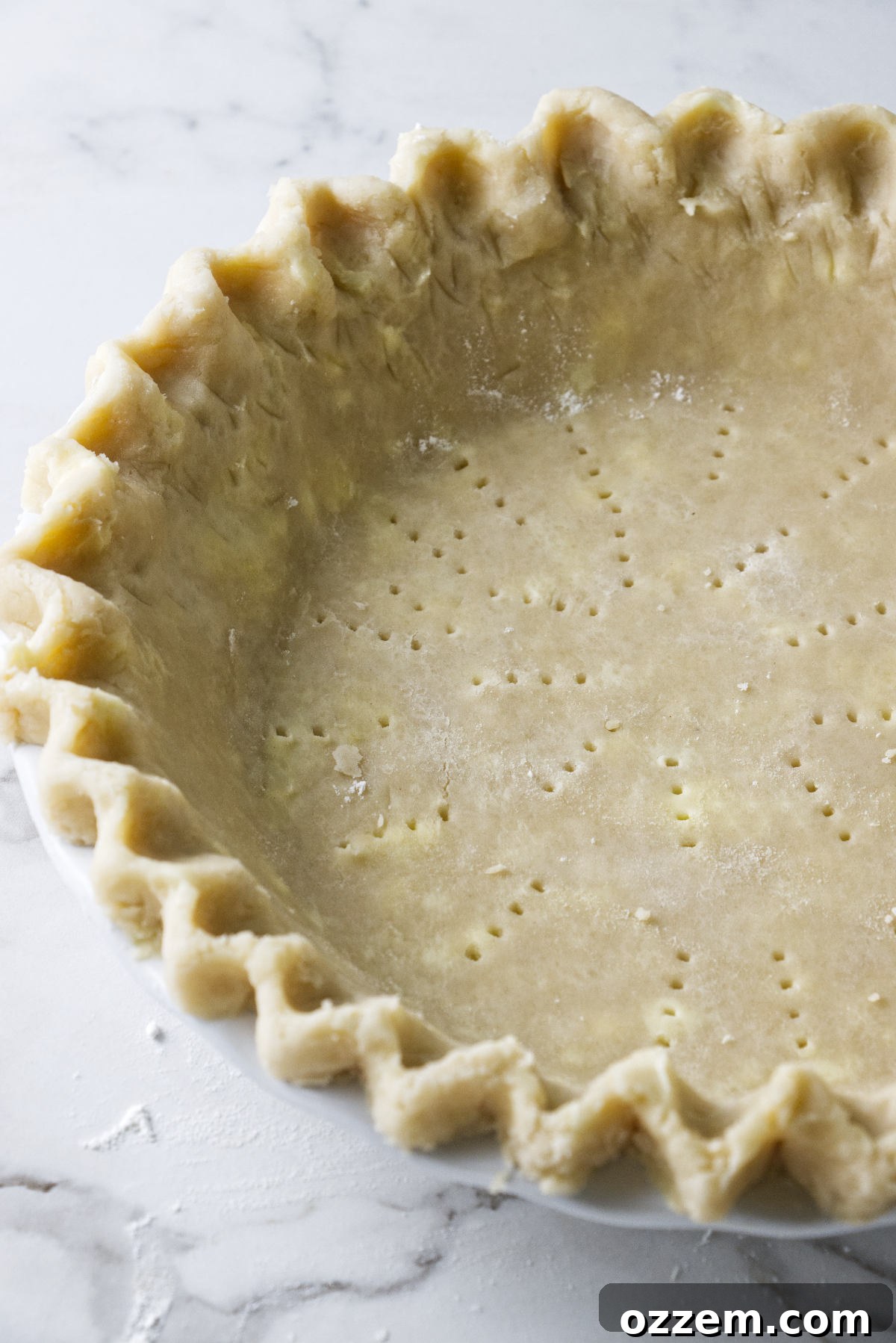 Unbaked, raw Crisco pie dough resting in a silver pie plate, edges neatly crimped, ready for filling and baking.