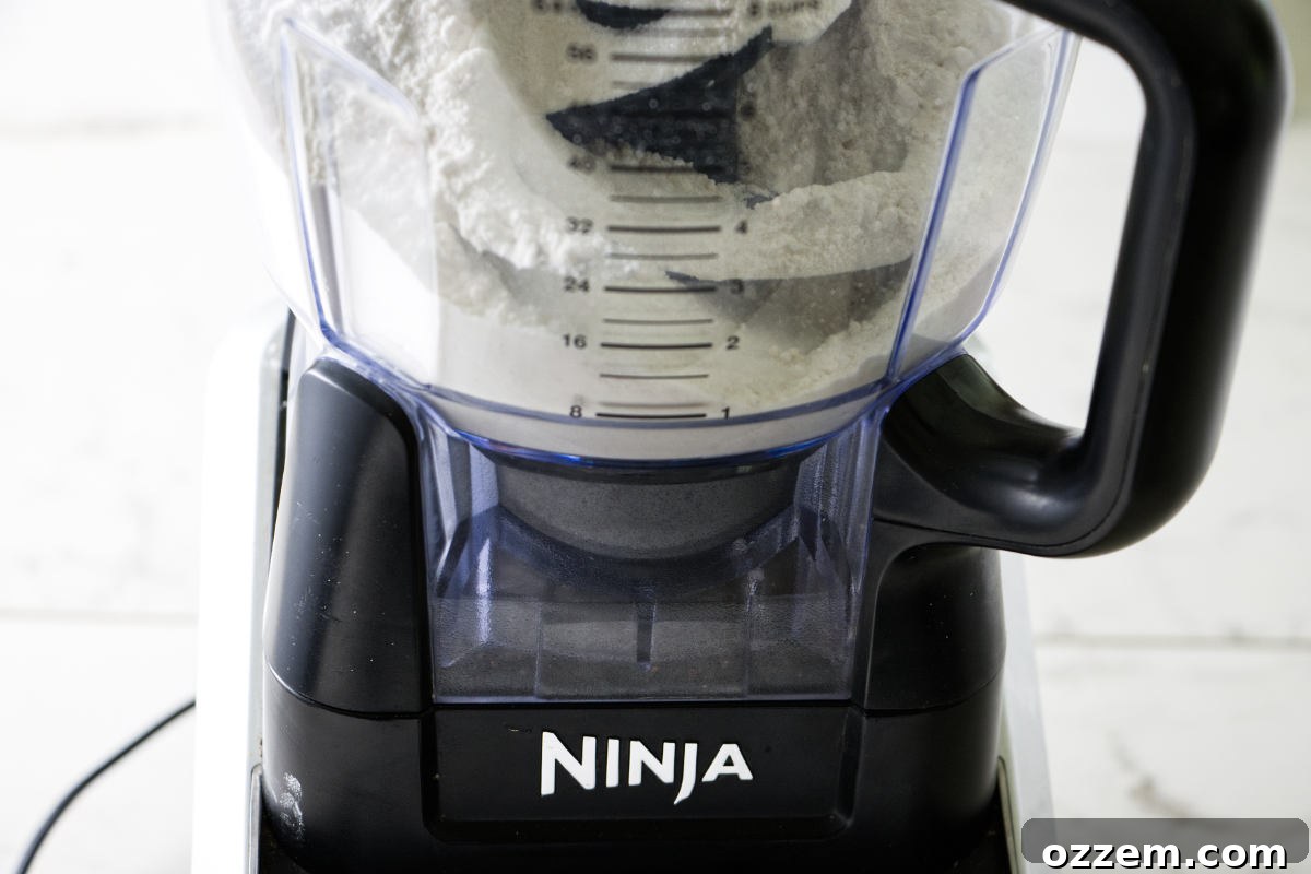 Blending dry ingredients like flour, sugar, and salt in a Ninja food processor for the Crisco pie crust.