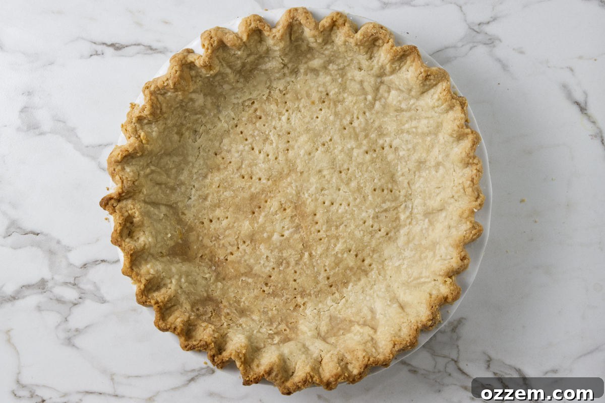 A freshly baked, golden-brown pie crust lined with parchment paper and pie weights for blind baking.