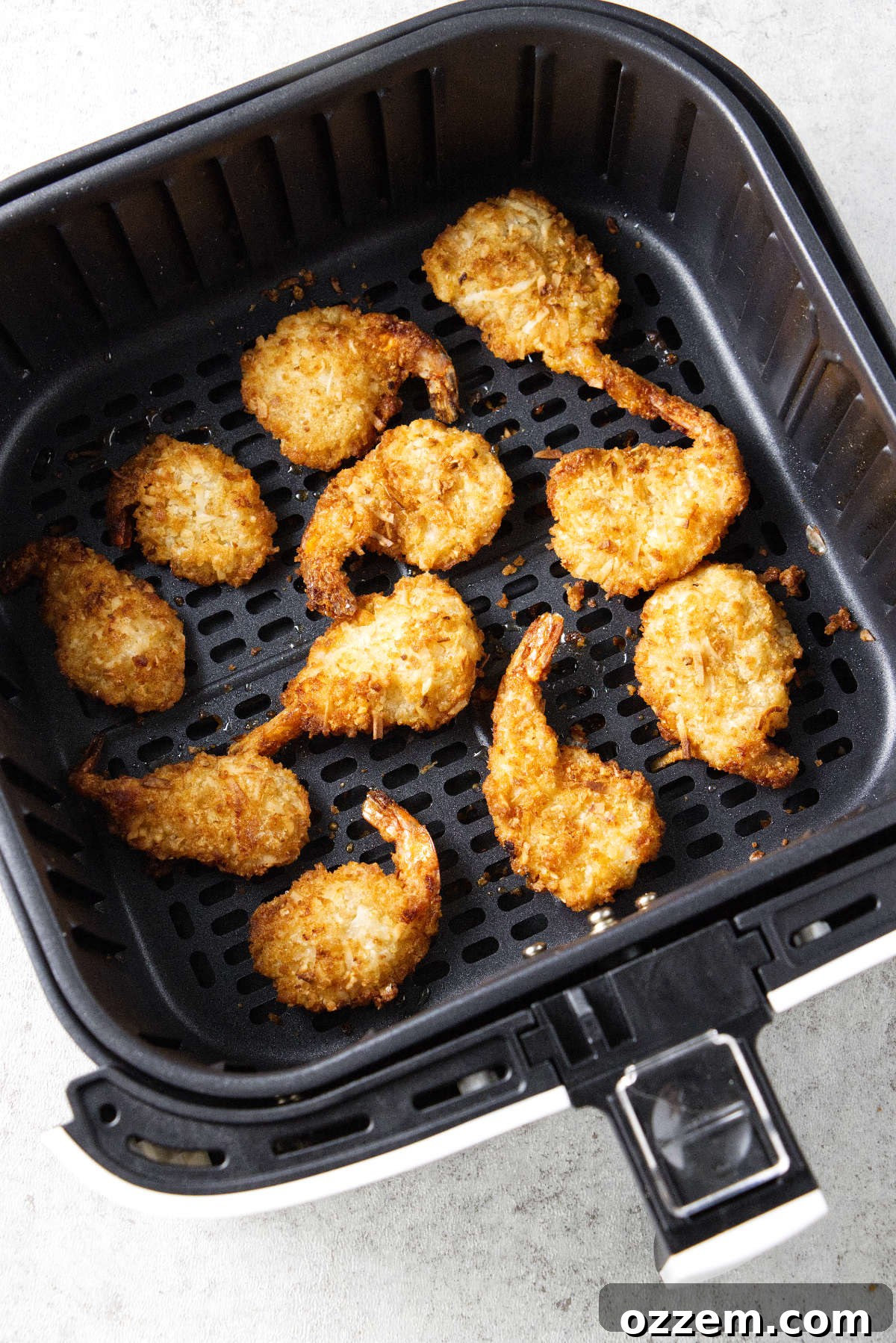 Crispy Air Fryer Frozen Coconut Shrimp 3 Coconut shrimp in an air fryer basket.