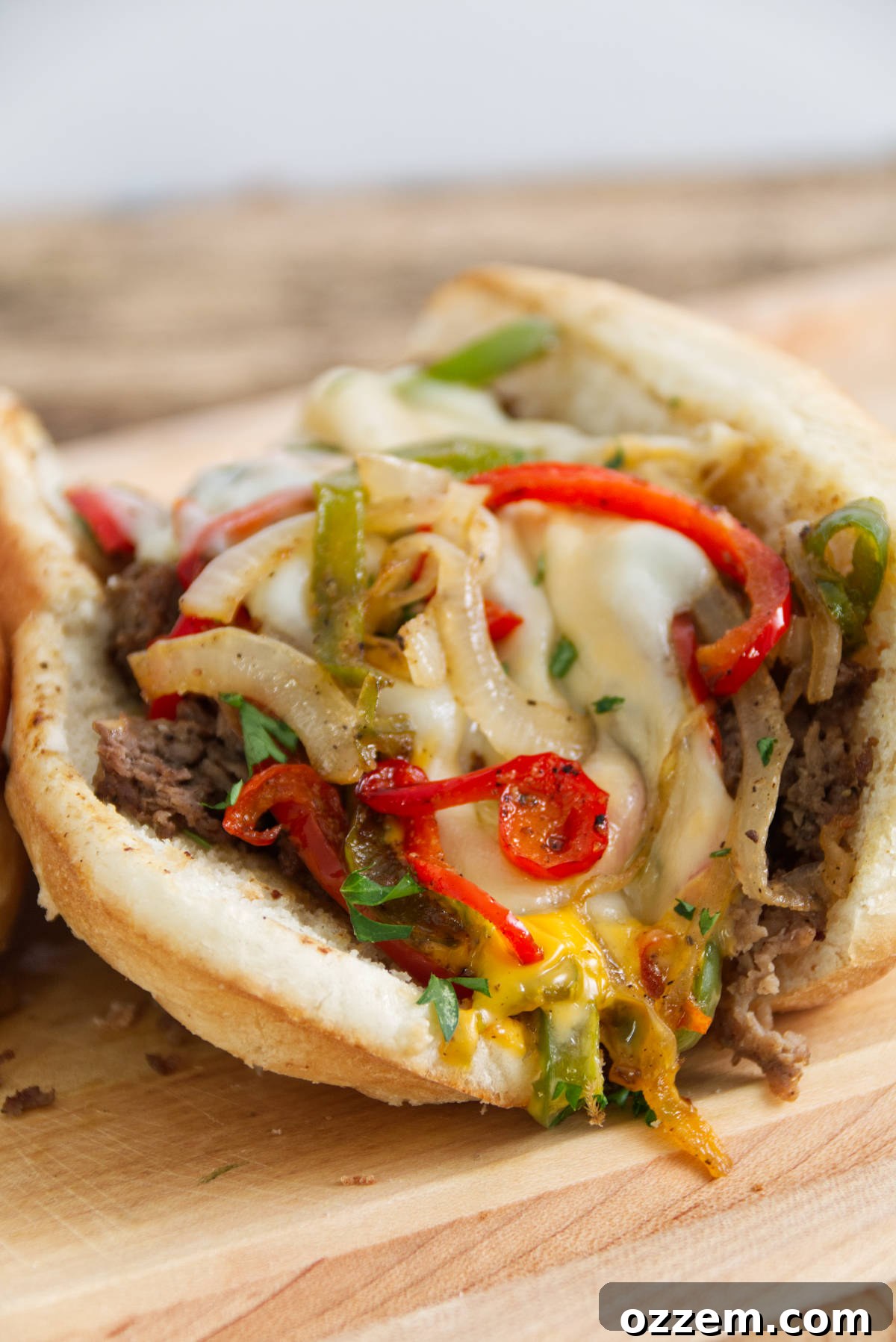 Sizzling Griddle Philly Cheesesteak 2 Close up of a Blackstone Philly Cheesesteak loaded with green and red peppers, melted provolone cheese, thinly sliced steak, and golden Cheese Whiz on a perfectly toasted hoagie roll