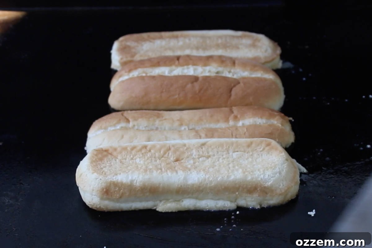 Sizzling Griddle Philly Cheesesteak 6 Butter-brushed hoagie rolls expertly toasting on the Blackstone griddle, achieving a perfect golden crisp.