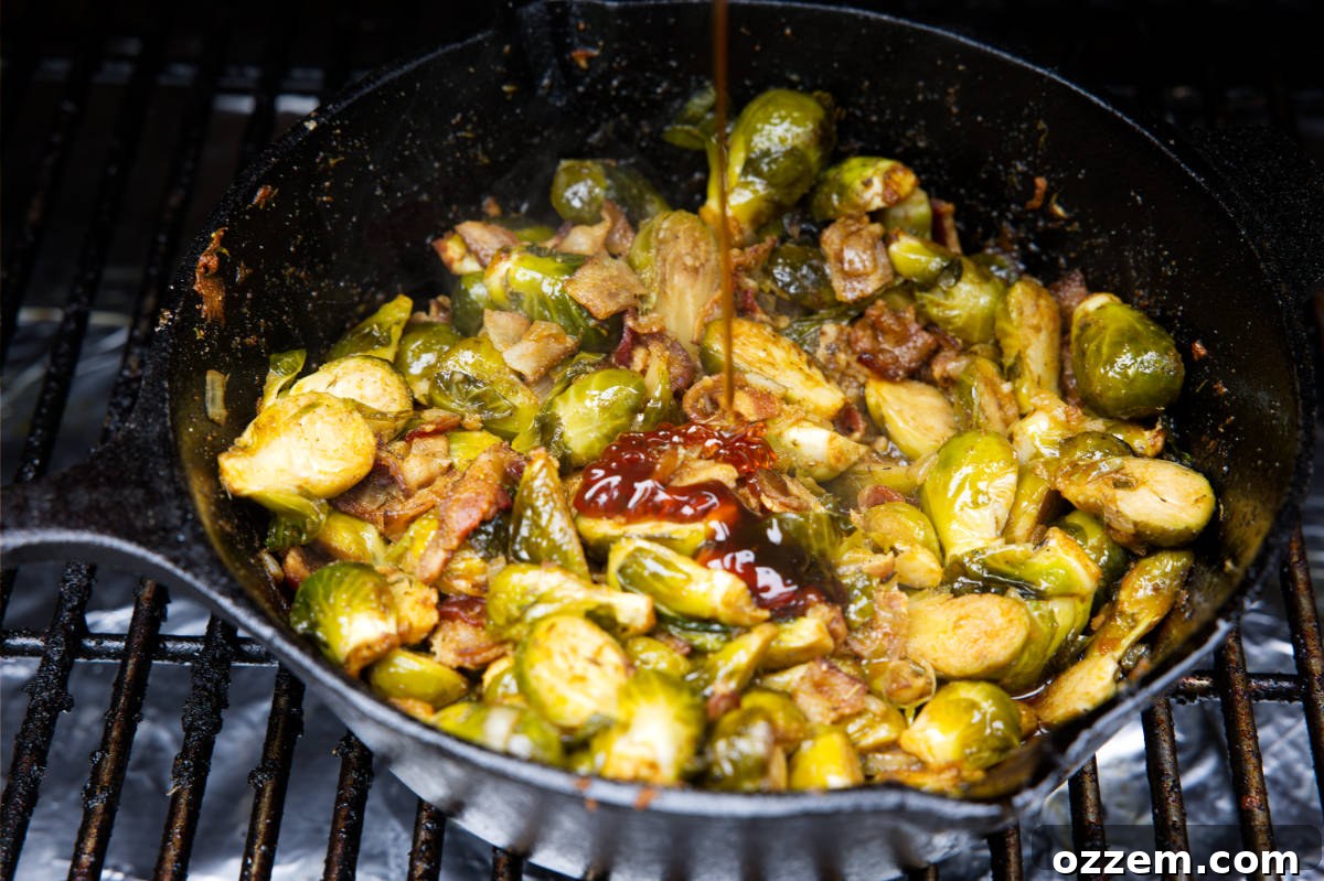 Smoked Brussels sprouts in a skillet with a beautiful drizzle of hot honey being added