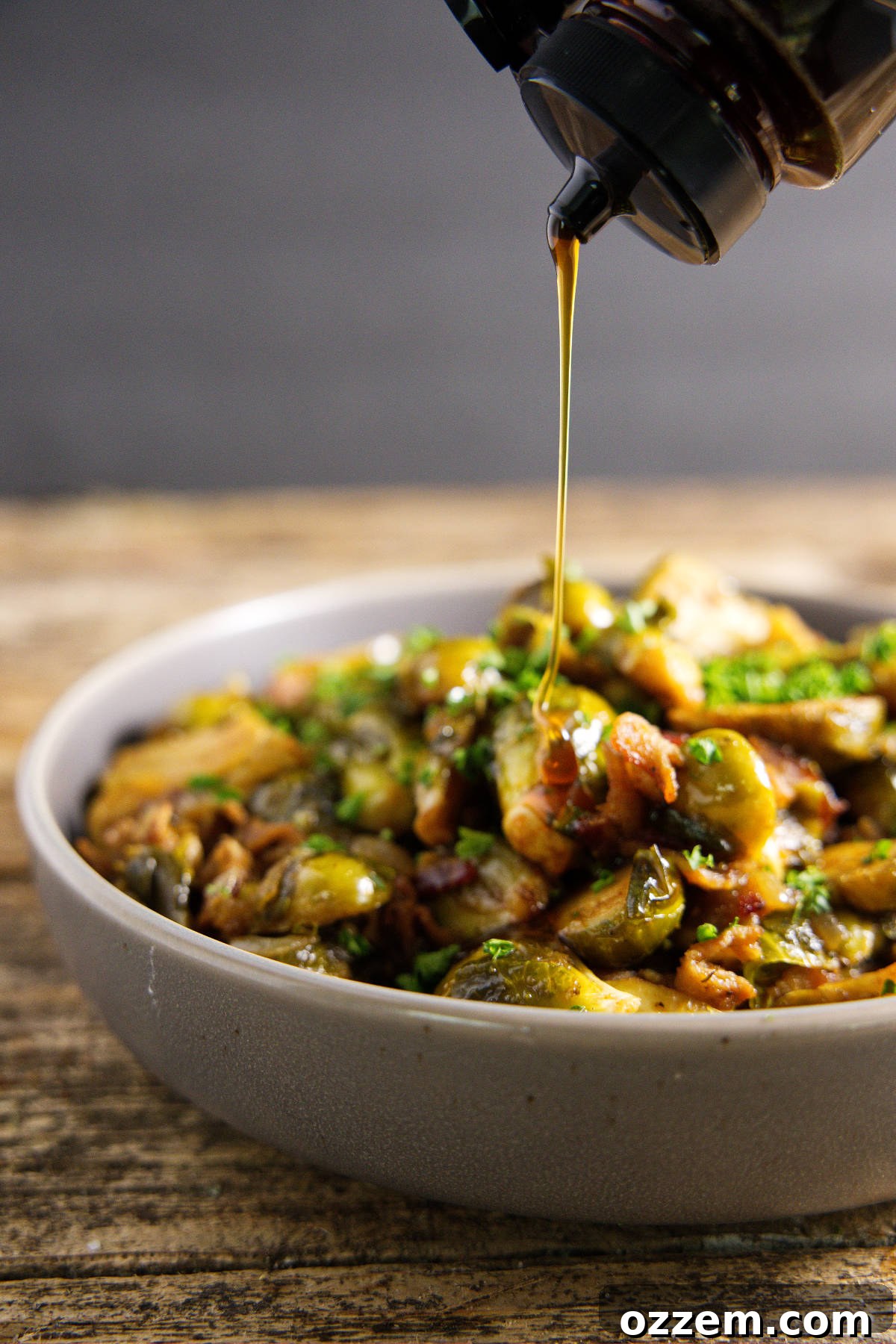 Close-up of hot honey drizzling over a bowl of smoked Brussels sprouts