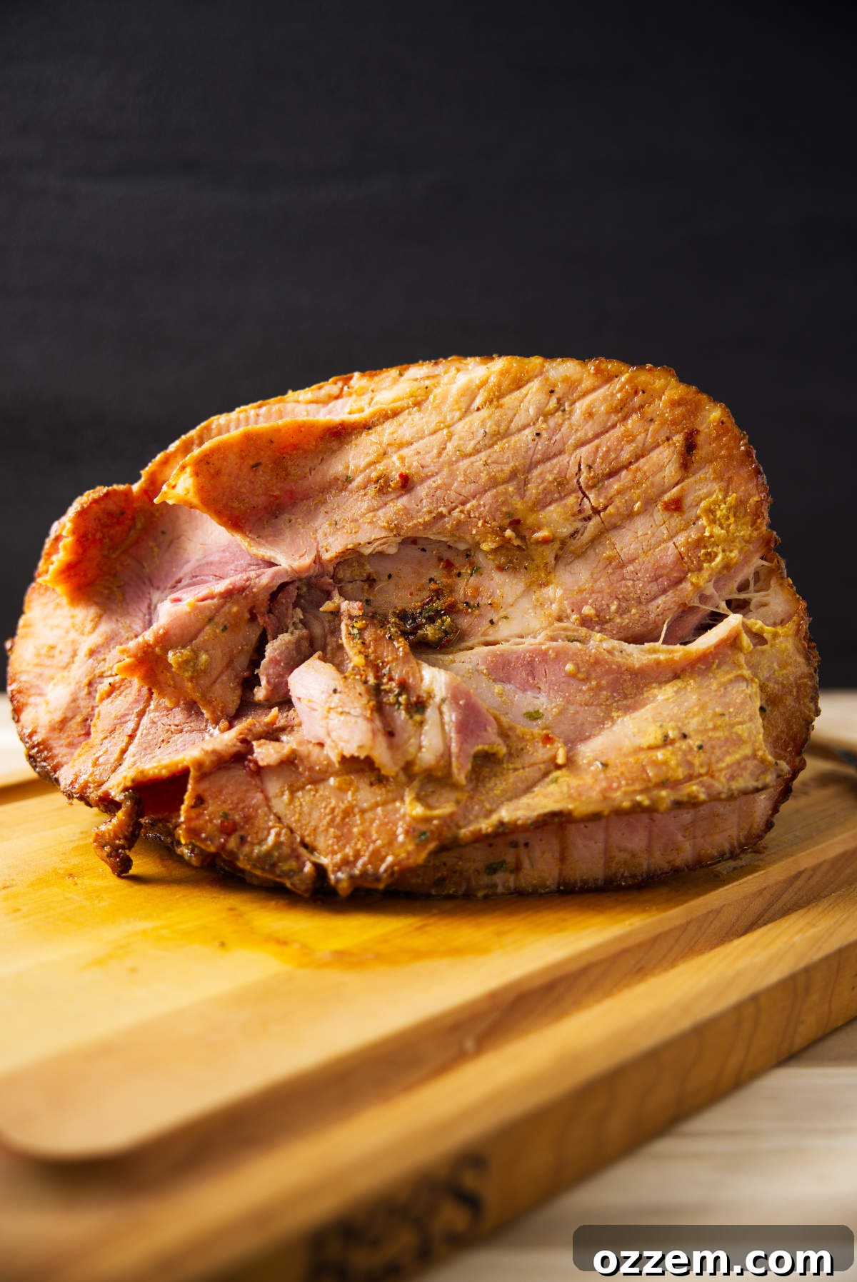A beautifully spiral sliced twice smoked ham, with a rich, glossy glaze, resting on a rustic butcher block, ready to be carved.