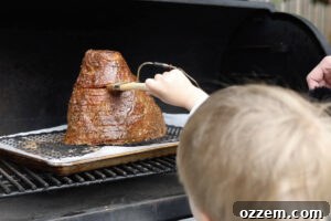 Brushing glaze on the ham while it is on the Traeger.