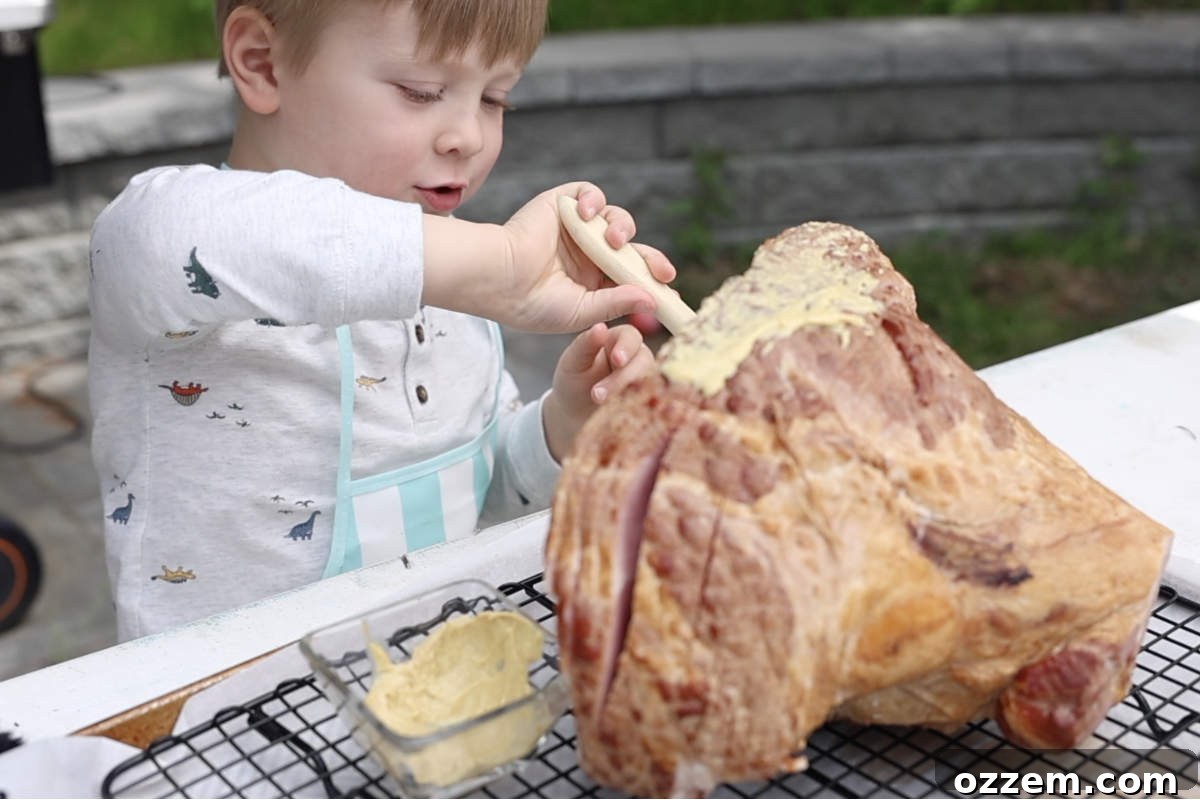 Brushing a spiral-cut ham with yellow mustard as a binder before seasoning.