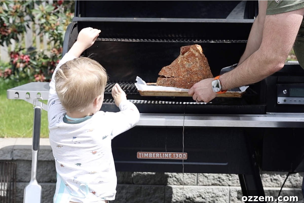 Placing the seasoned spiral-cut ham onto the grill grates of a Traeger smoker for the initial smoking phase.