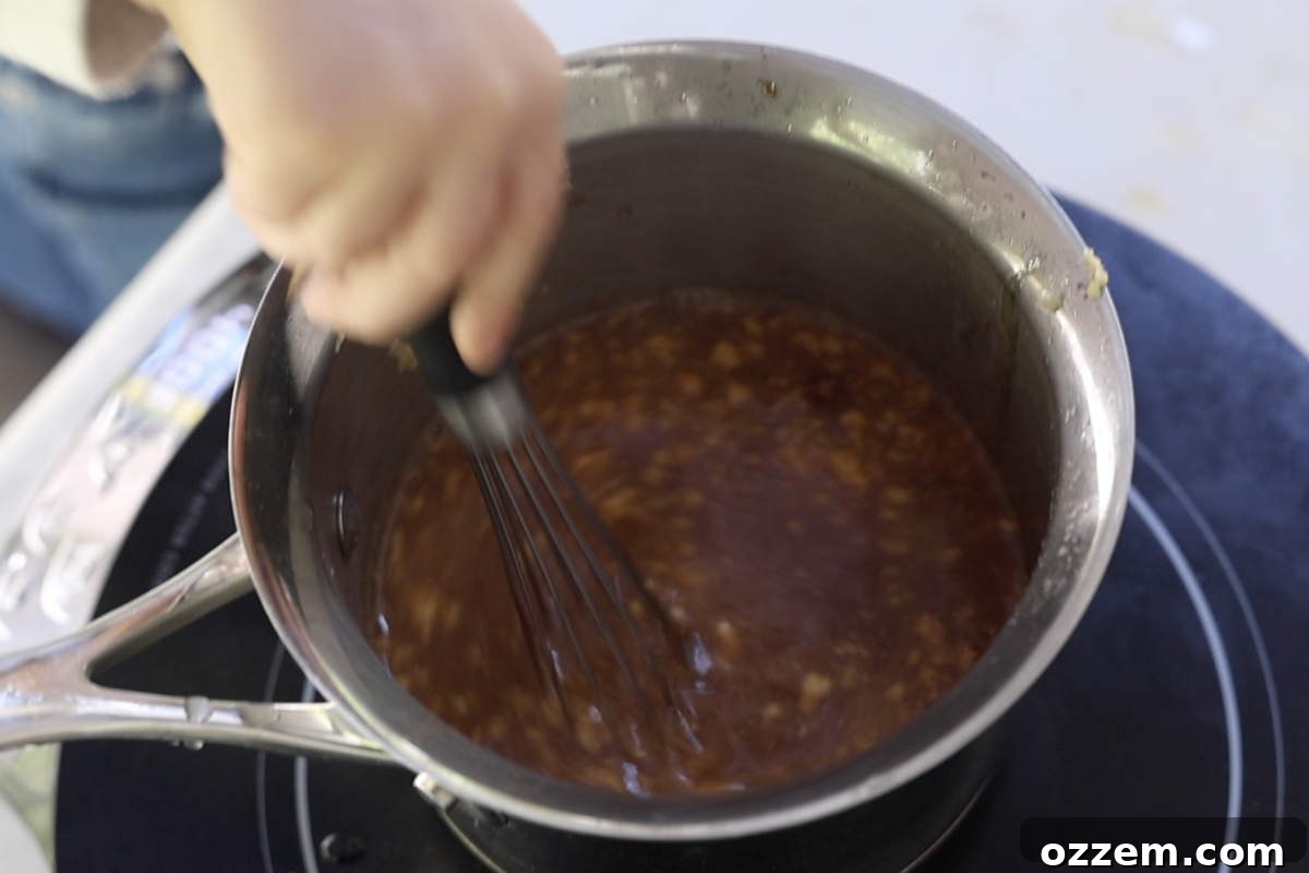A pineapple bourbon glaze simmering in a saucepan on the stovetop, thickening to a perfect consistency.