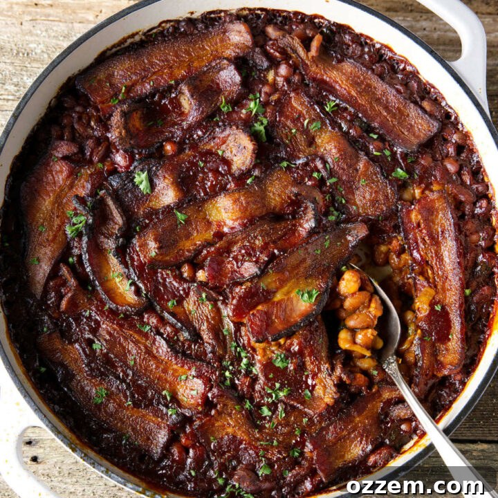 Smoked baked beans in a Dutch oven with bacon laid on top