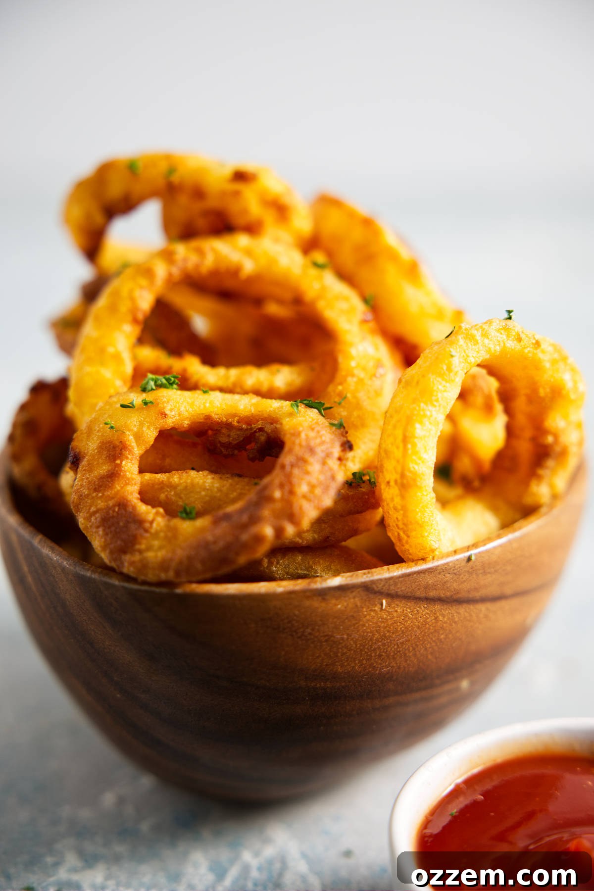 Crispy Air Fryer Frozen Onion Rings 5 Wooden bowl filled with onion rings, bowl of ketchup