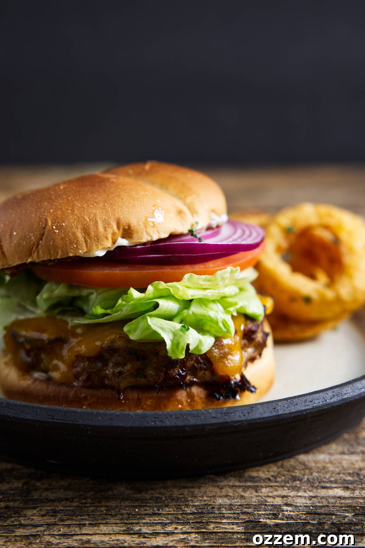 A close-up of a fully assembled turkey burger on a brioche bun with fresh toppings, showcasing its juicy patty and melted cheese.