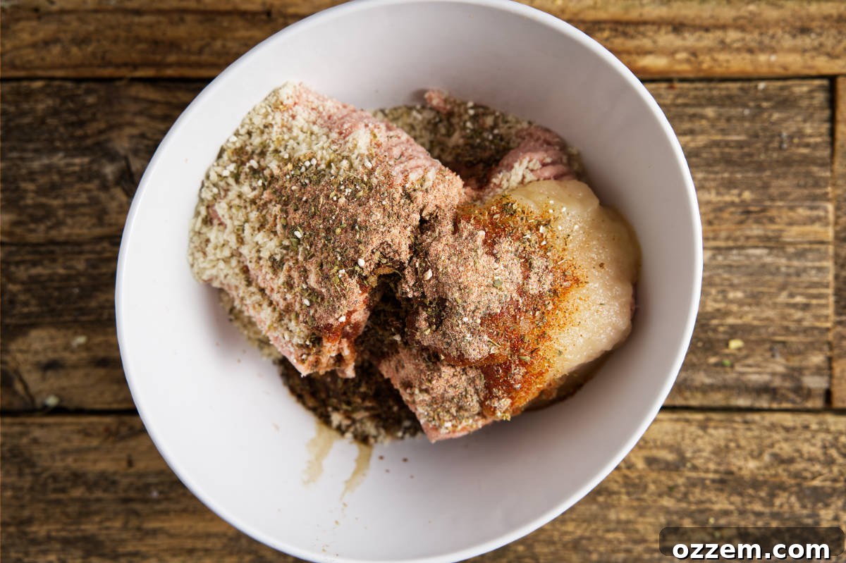 Mixing the ground turkey, seasoning, applesauce, breadcrumbs, and Worcestershire sauce in a large bowl with a spoon.