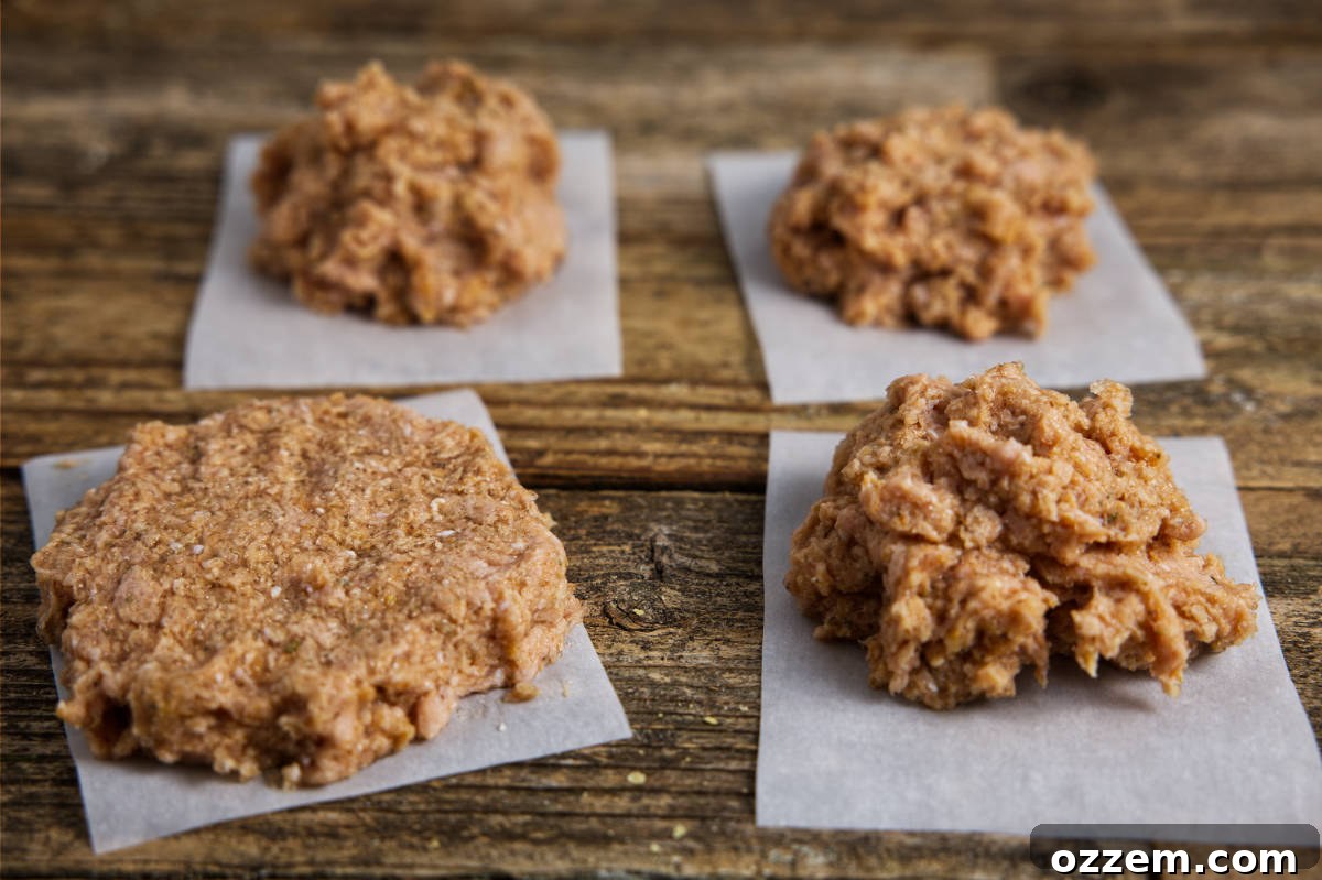 Forming turkey burger patties into four equally sized portions and lining them with parchment paper.