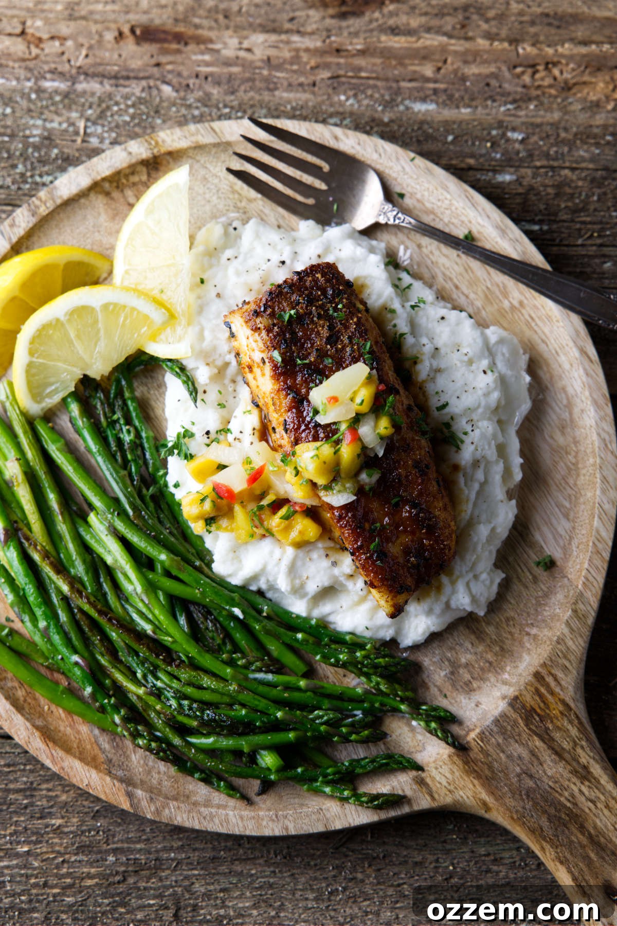 air fryer halibut plated on a bed of mashed potatoes and asparagus with mango salsa