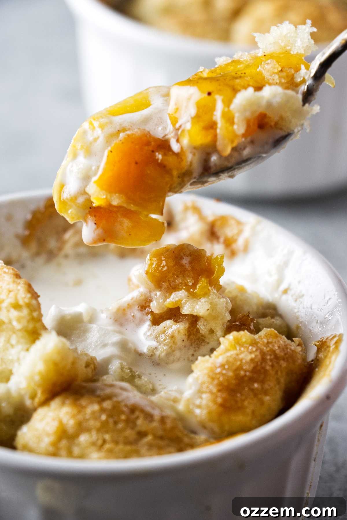 fork with peach hovering over a ramekin filled with peach cobbler