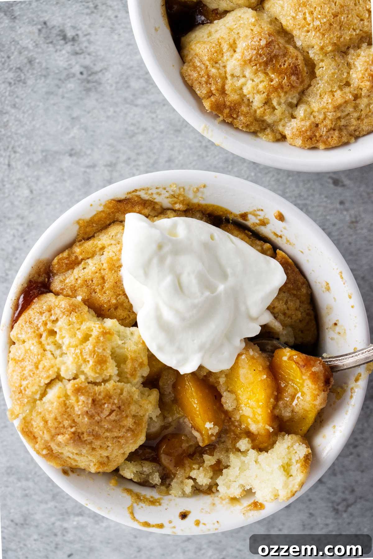 ramekin of air fryer peach cobbler with a dollop of whipped cream