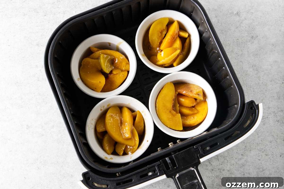 peach cobbler filling in ramekins in the air fryer basket