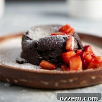 Air fryer mug cake plated with chopped strawberries and dusted with powdered sugar.