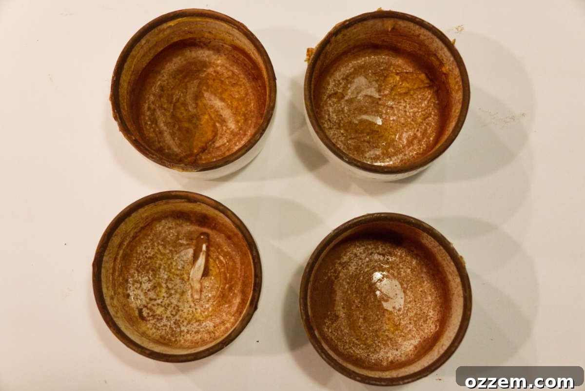 Preparing mugs with butter and cocoa powder.