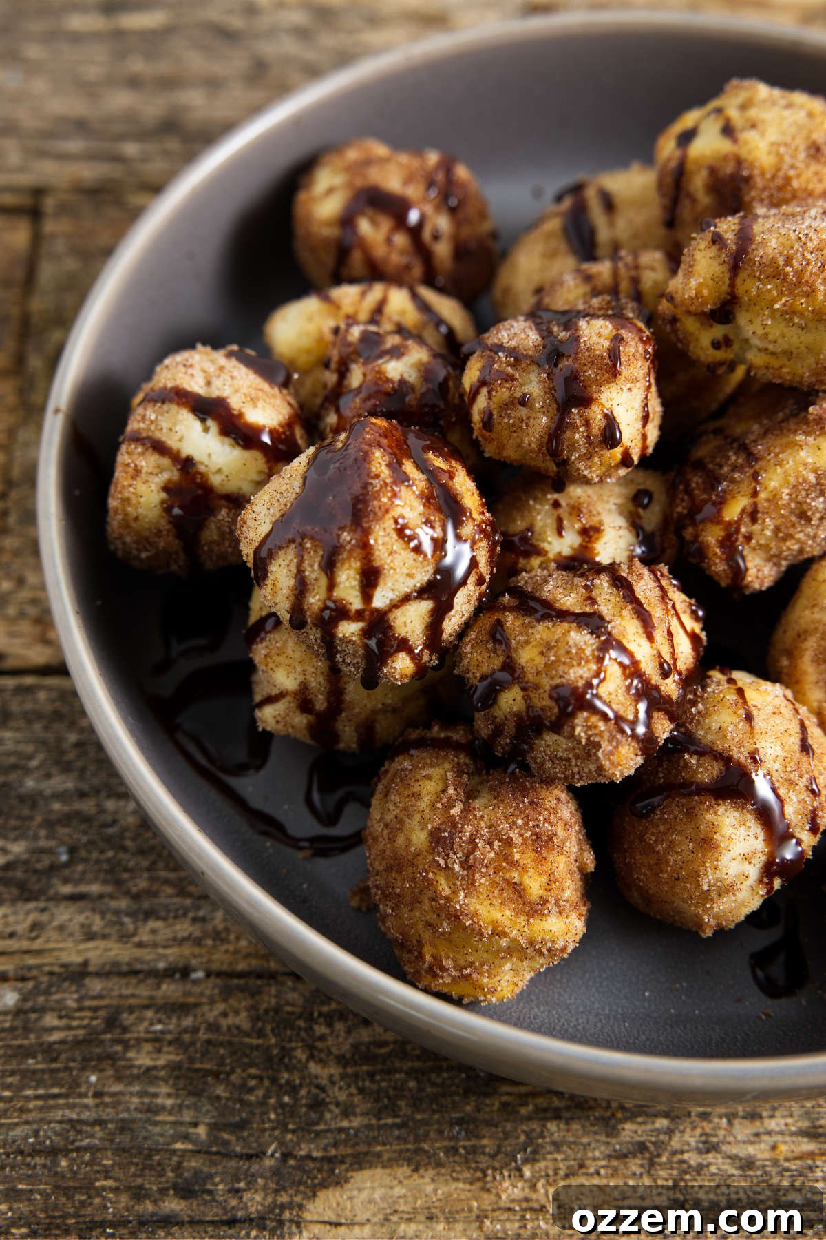 Golden Air Fryer Doughnut Bites 15 donut holes in bowl drizzled with chocolate sauce