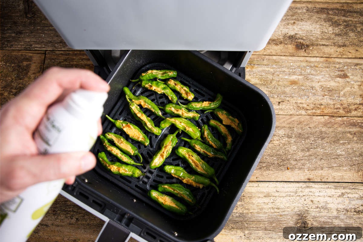 Stuffed shishito peppers in an air fryer basket, ready for cooking