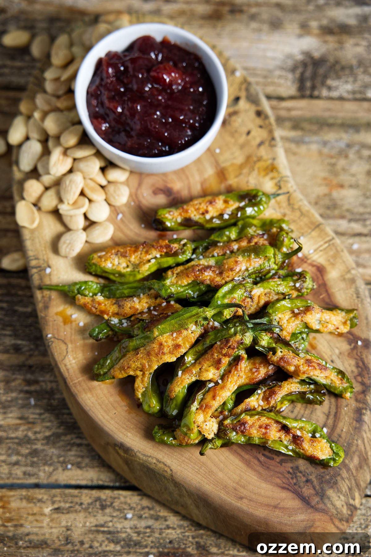 Air fryer shishito peppers on cutting board with cherry preserves and almonds, ready to serve