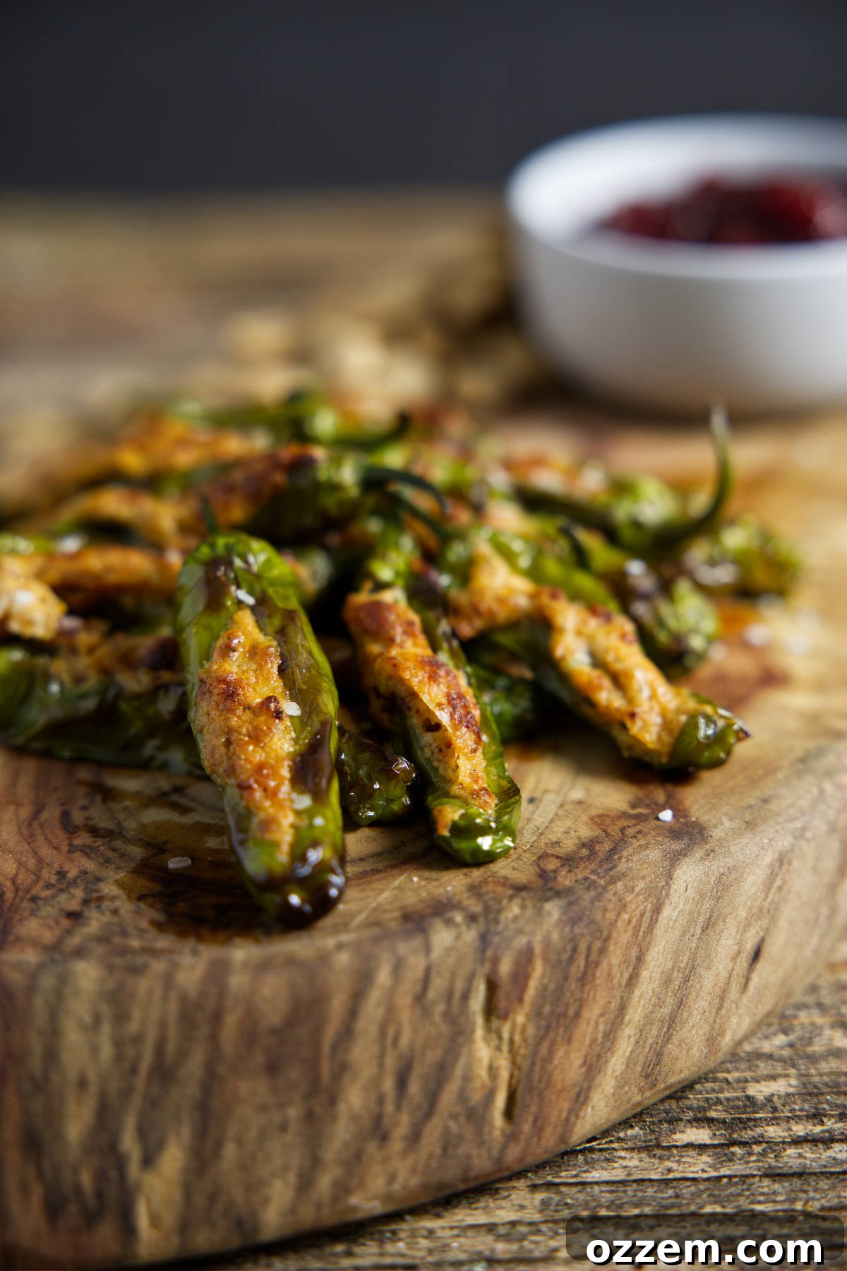 Close up of air fryer shishito peppers, showing the charred skin and melted cheese