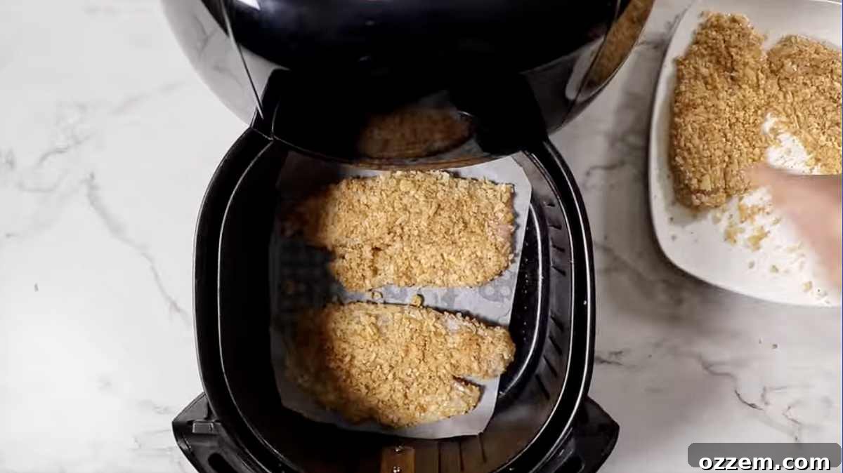 Golden brown, crispy air-fried tilapia fillets resting in an air fryer basket, ready to be served.