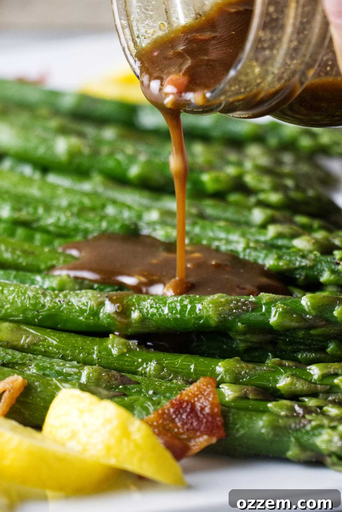 Crispy Air Fryer Frozen Asparagus 3 Drizzling vinaigrette over cooked asparagus on a plate.