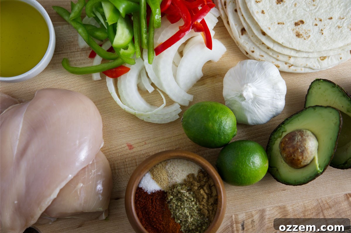 A vibrant display of fresh ingredients for Blackstone Fajitas, including sliced chicken breast, colorful bell peppers, yellow onions, limes, avocado, garlic, various spices, and a stack of tortillas.