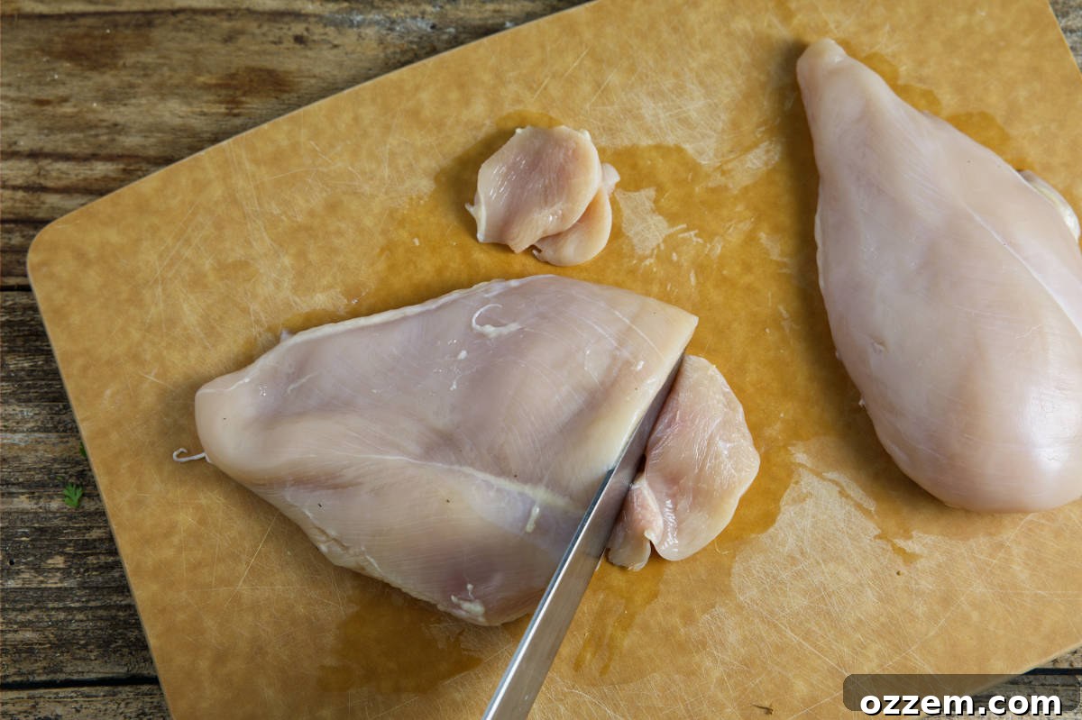 Chef thinly slicing a boneless, skinless chicken breast on a cutting board, preparing it for the fajita marinade.