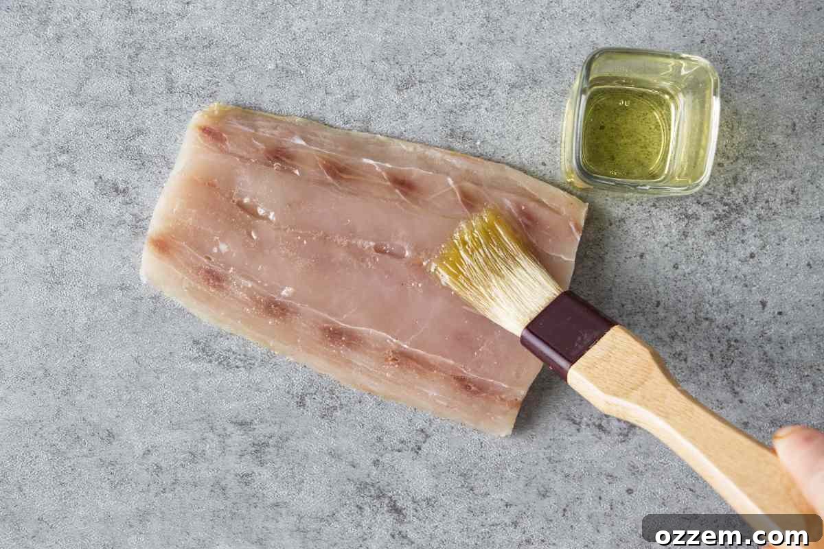 Golden Air Fryer Mahi Mahi 6 A cooking brush applying a thin, even layer of oil to a mahi mahi fillet, ensuring seasoning adherence.