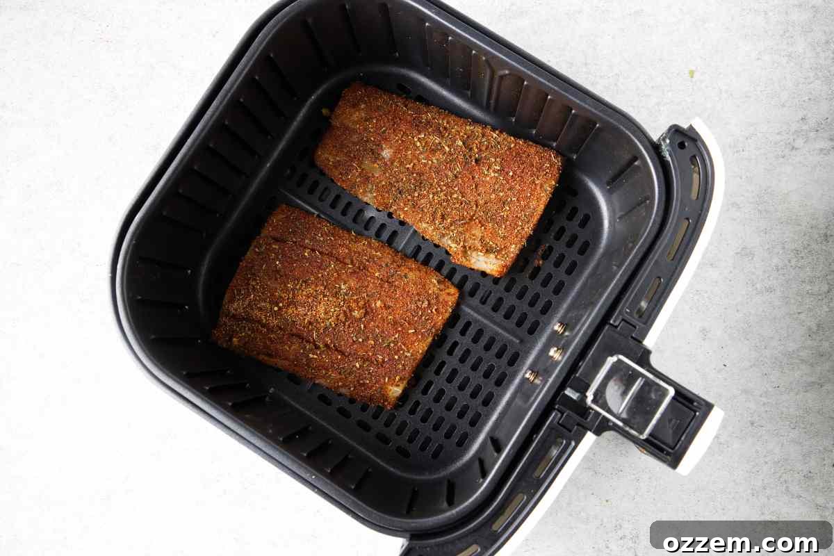 Golden Air Fryer Mahi Mahi 8 Two seasoned mahi mahi fillets neatly arranged in an air fryer basket, ready to cook.