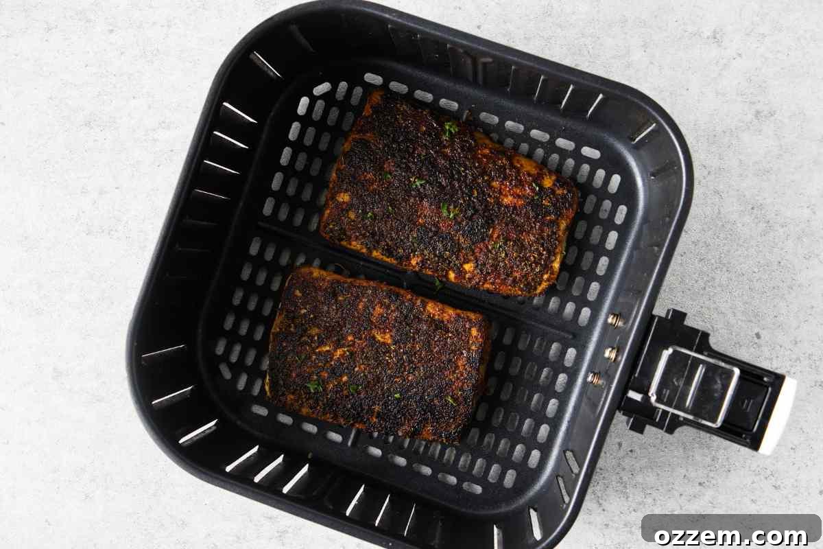 Golden Air Fryer Mahi Mahi 9 Two partially cooked mahi mahi fillets in an air fryer basket, showing a developing crust, after being flipped.
