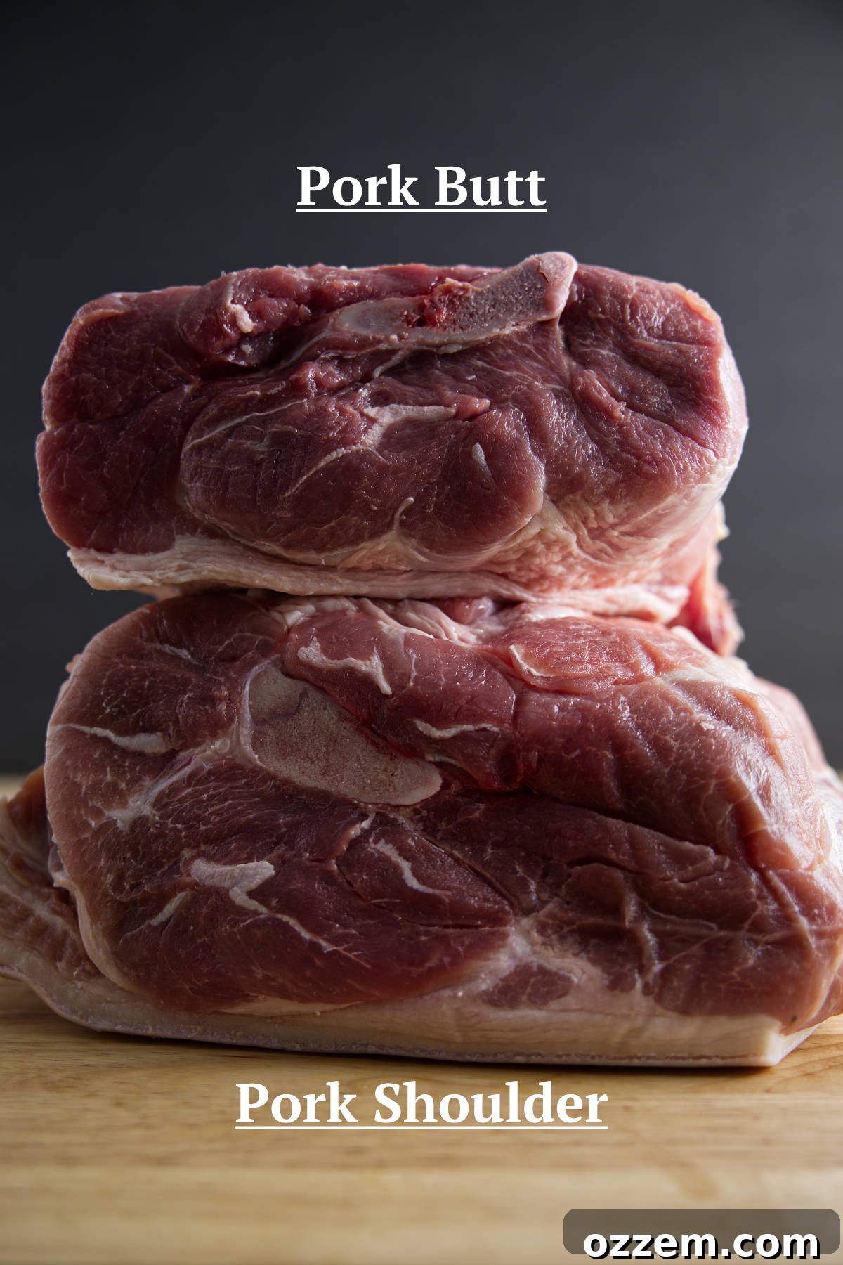 Pork shoulder (picnic shoulder) and pork butt (Boston butt) stacked on a butcher block, showcasing their differences.