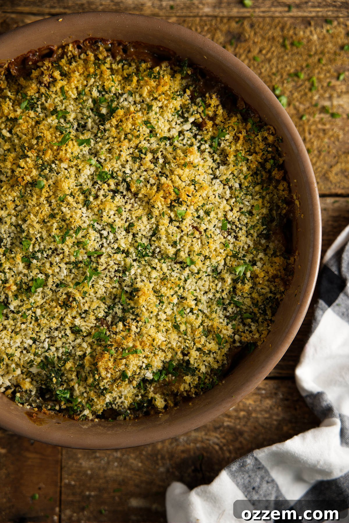 Overhead view of a golden brown Smoked Green Bean Casserole, topped with a rustic herb breadcrumb mixture and freshly chopped herbs, ready to be served from the smoker.