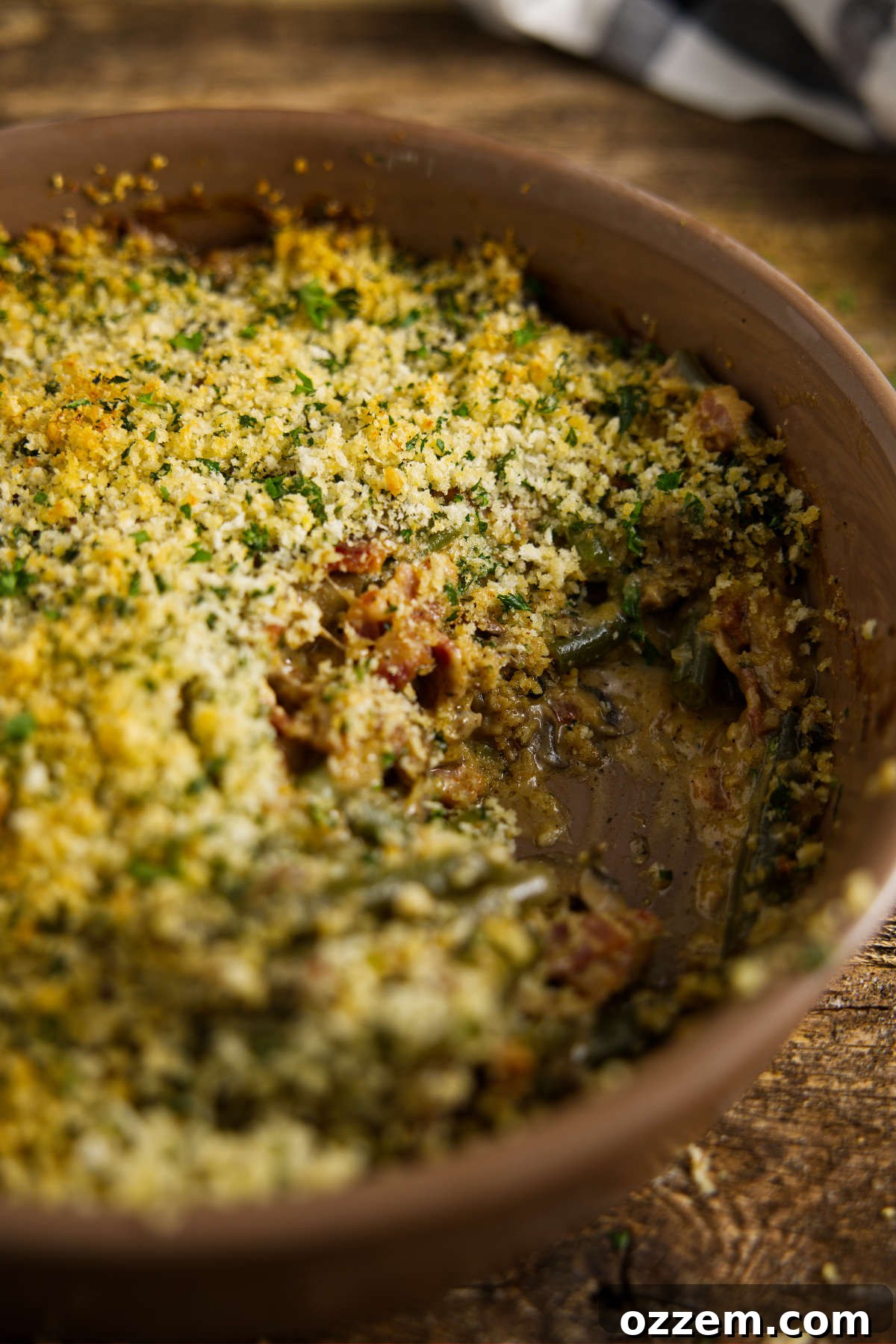 A casserole dish with a scoop missing from the smoked green bean casserole, showcasing the rich texture and tantalizing aroma of the dish.