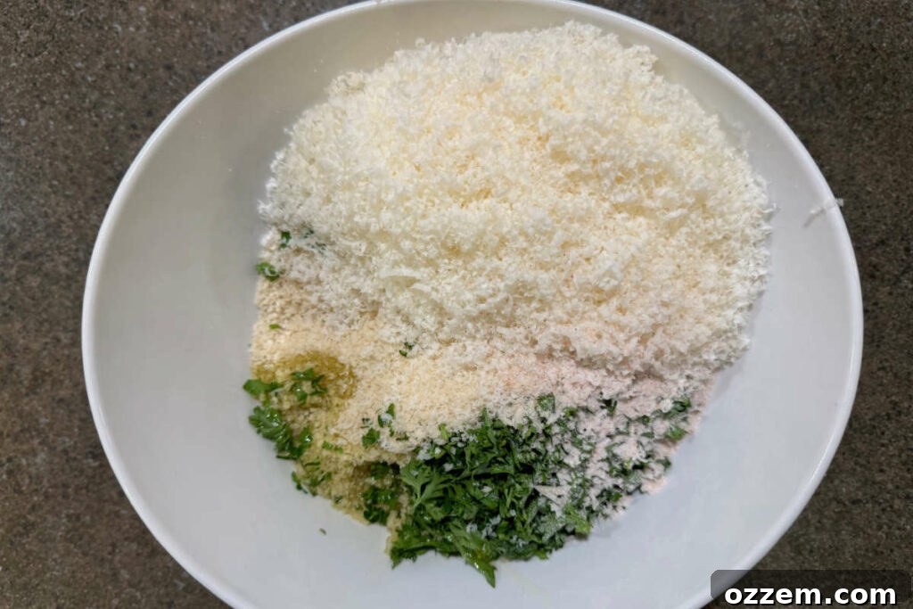 A bowl containing Panko breadcrumbs, grated Parmesan cheese, fresh parsley, olive oil, and seasonings being mixed together to create the casserole topping.